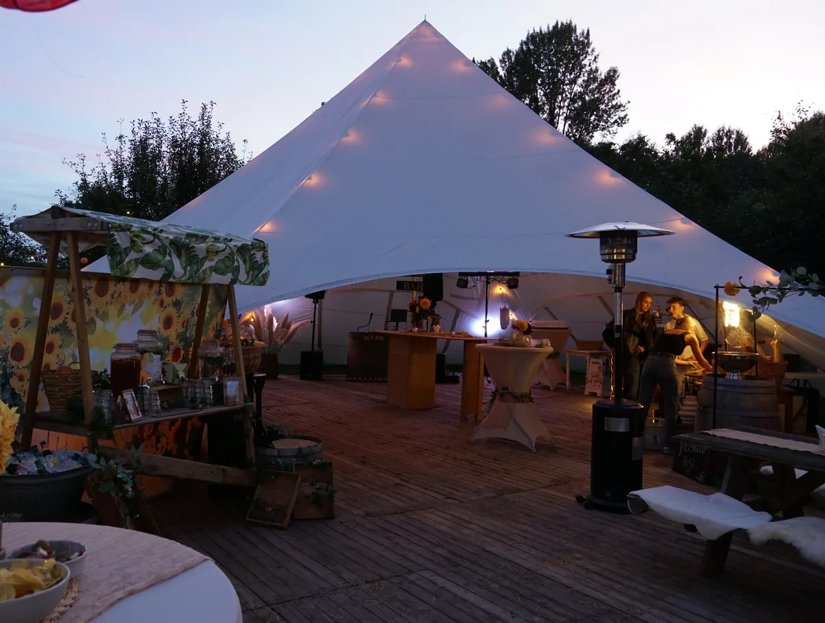 Sfeervolle feestlocatie met witte feesttent en houten terras voor een bruiloft of feest
